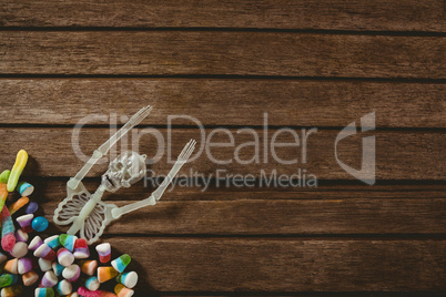 Skeleton decoration with candies on wooden table