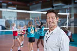 Smiling coach standing in the volleyball court