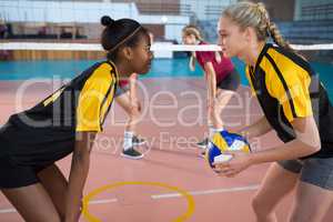 Female players looking face to face while playing volleyball