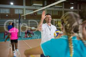 Coach giving high five to female player in volleyball court