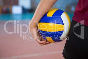 Female player holding volleyball in the court