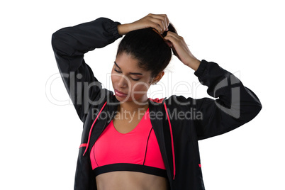 Female athlete tying hair against white background