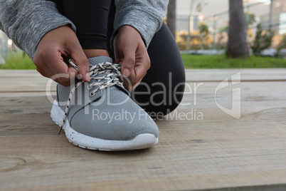 Low section of female athlete tying shoelace