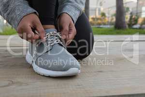 Low section of female athlete tying shoelace