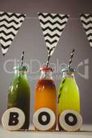 Cookies with boo text by colorful drinks in bottles