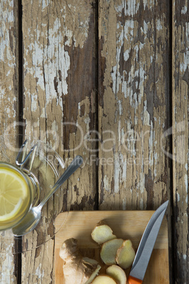 Overhead view of fresh ginger tea by cutting board on weathered table