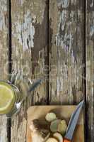 Overhead view of fresh ginger tea by cutting board on weathered table
