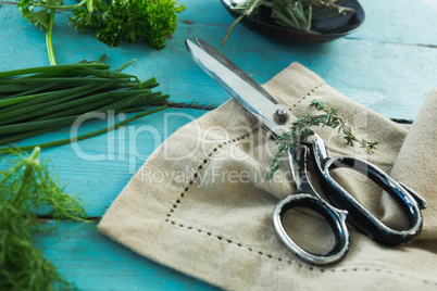 Various herbs, scissors and napkin on wooden table