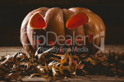 Close up of jack o lantern with autumn leaves