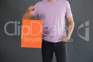 Man holding shopping bag against grey background