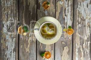 Overhead view of lemon and mint leaves in ginger tea on table