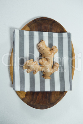 Directly above view of fresh ginger on striped napkin in wooden plate