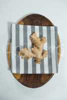 Directly above view of fresh ginger on striped napkin in wooden plate