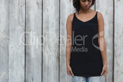 Sad young woman standing against wooden wall