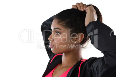 Female athlete looking away while tying hair