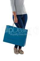 Low section of woman holding blue shopping bag