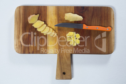 Directly above view of chopped gingers and knife on wooden cutting board