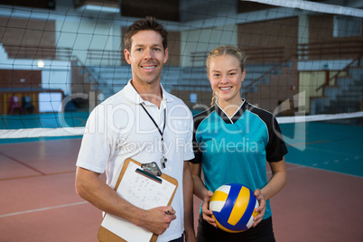 Happy male coach and volleyball player standing in the court