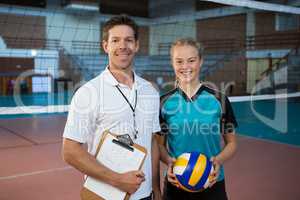 Happy male coach and volleyball player standing in the court