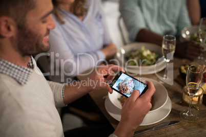 Man taking photo of meal with mobile phone