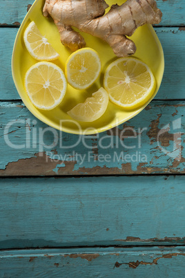 Lemon slices and ginger in yellow plate on table