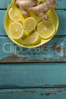 Lemon slices and ginger in yellow plate on table