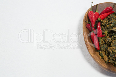 High angle view of red chili pepper and dried kale in wooden plate