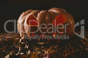 illuminated jack o lantern with leaves on table during autumn