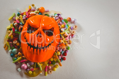 Monster mask with various candies over white background