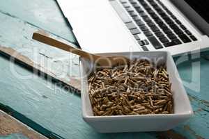 Bowl of cereal bran sticks with spoon and laptop