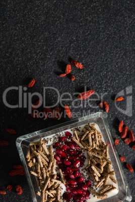 Yogurt, cereal bran sticks and pomegranate seeds in tray with dried fruits