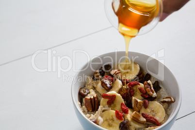 Honey pouring into a fruit cereal bowl