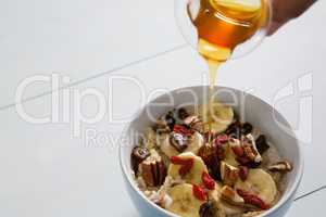 Honey pouring into a fruit cereal bowl