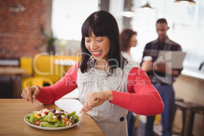 Happy young woman eating fresh healthy salad at coffee shop