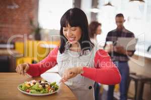 Happy young woman eating fresh healthy salad at coffee shop