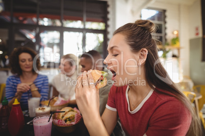 Close up of beautiful young woman eating burger
