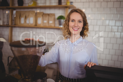 Portrait of smiling young waitress standing by coffee maker