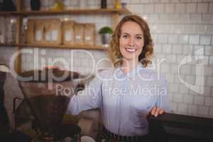 Portrait of smiling young waitress standing by coffee maker