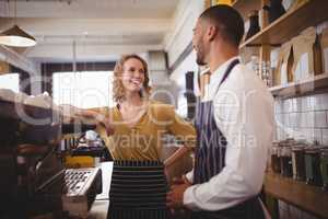 Smiling young waiter and waitress standing by espresso maker