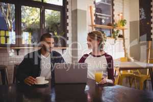 Young friends sitting with drinks and laptop at  coffee shop