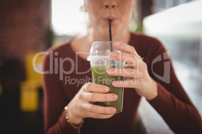 Midsection of woman drinking at cafe