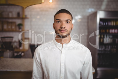 Portrait of confident young man standing at coffee shop