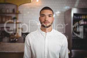 Portrait of confident young man standing at coffee shop