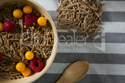 Bowl of cereal bran stick with golden berries and raspberries