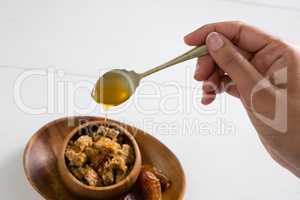 Womans hand pouring honey into cereal bowl