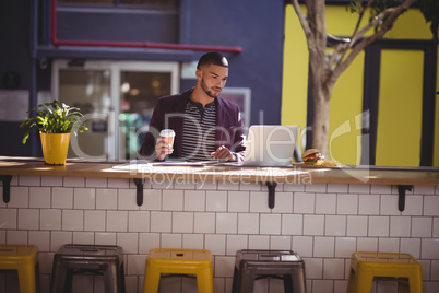 Handsome young male professional using laptop at coffee shop