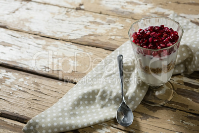 Cup of yogurt muesli and pomegranate with napkin and spoon