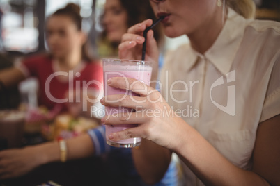 Midsection of woman drinking milkshake at cafe