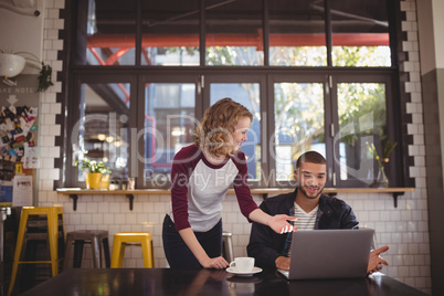 Young man and woman gesturing at laptop