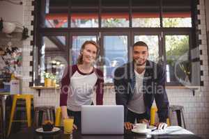 Portrait of smiling young man and woman standing at coffee shop